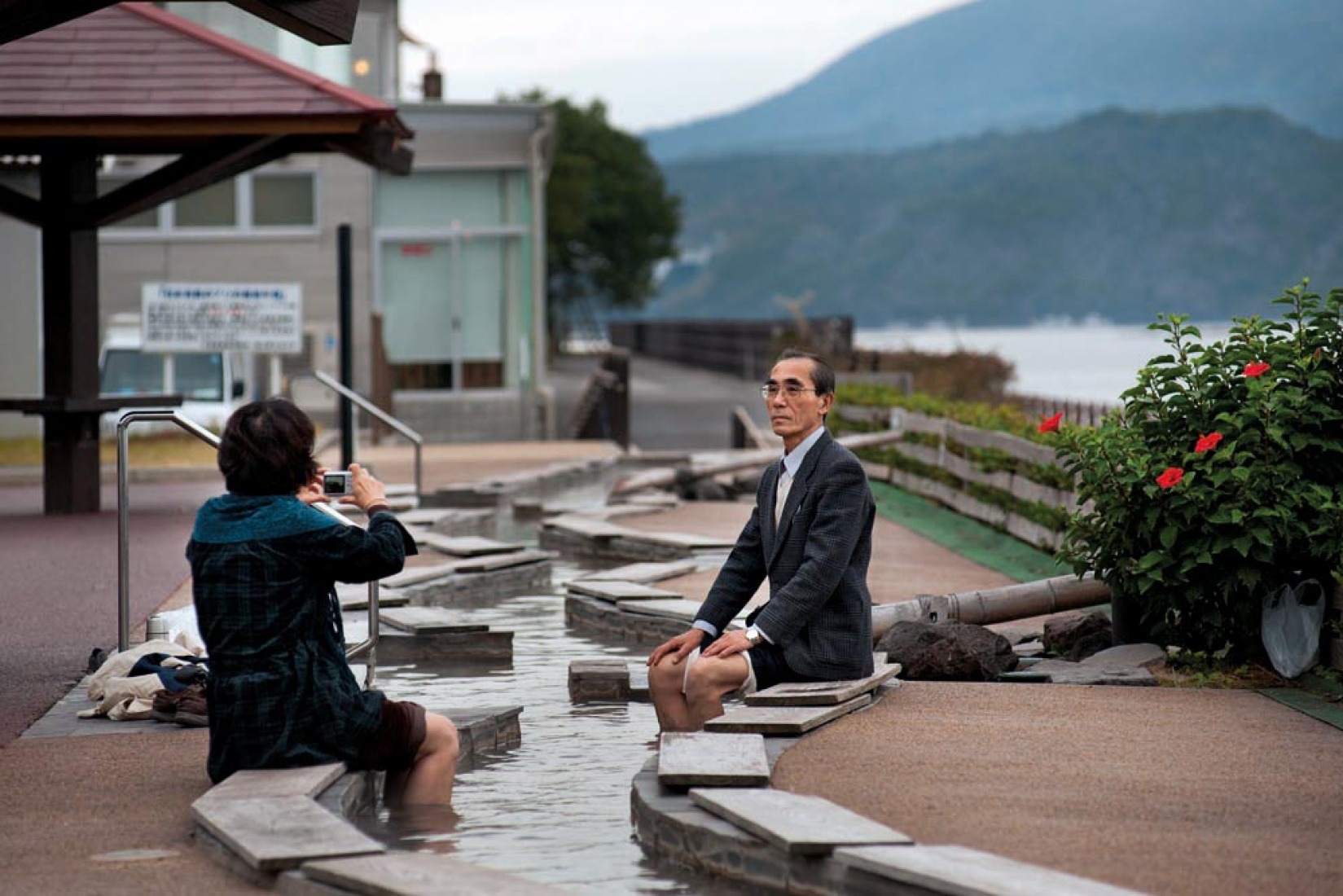 Turistas en un ashiyu, unas aguas termales para los pies, junto al volcán de Sakurajima. Tarumisu, Kagoshima, 2010. 桜島をバックに足湯を楽しむ観光客。鹿児島県垂水市、2010年。 COPYRIGHT:Tina Bagué