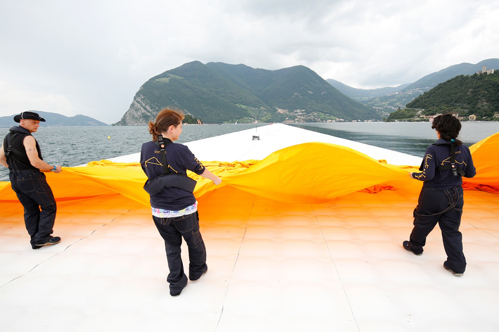 In the evening of June 15, hundreds of workers start to unfurl 1000,000 square meters of shimmering yellow fabric on the piers and pedestrian streets in Sulzano and Peschiera Maraglio. Image © Wolfgang Volz.