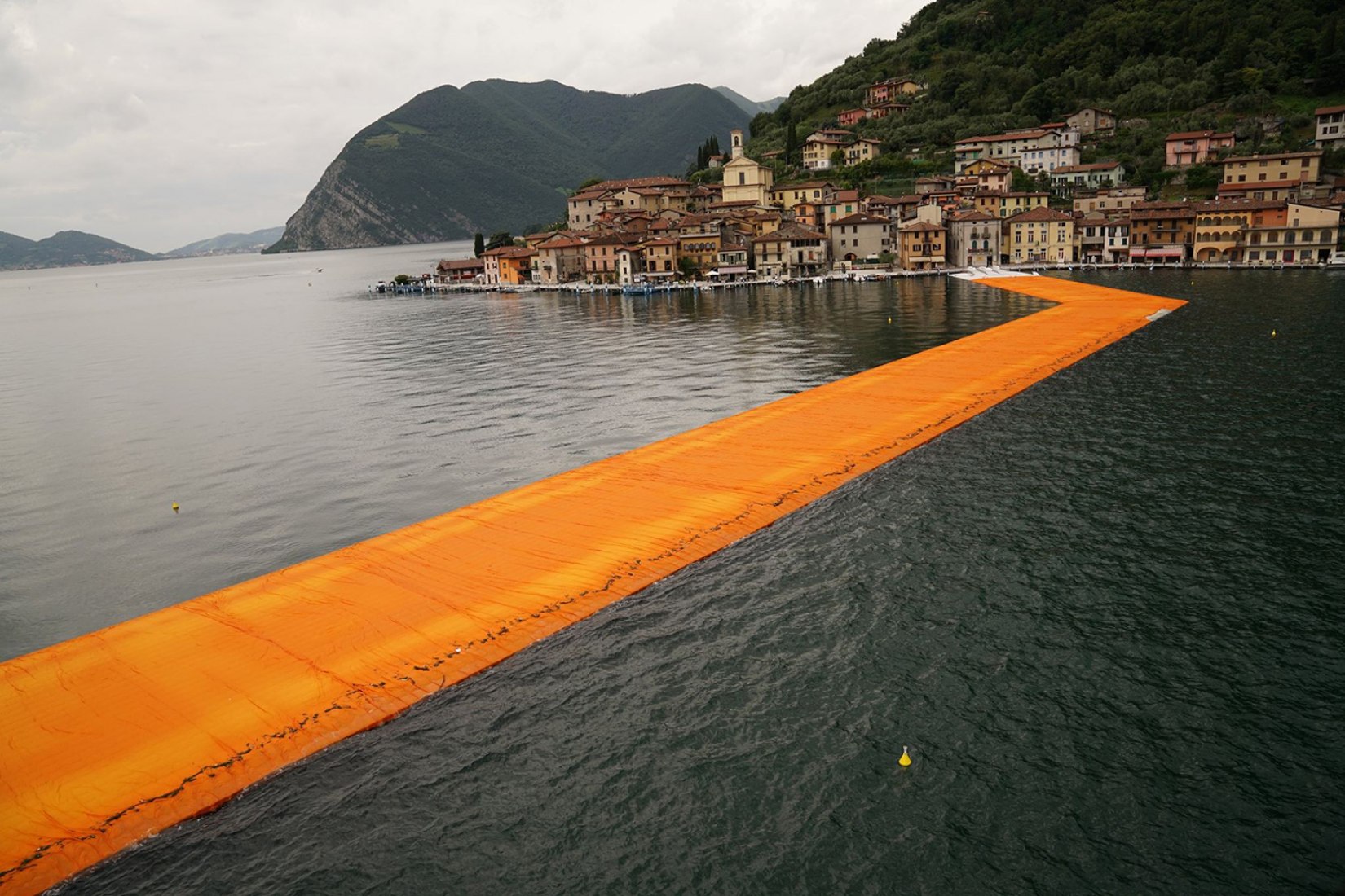 In the morning of June 16, unfurling of 1000,000 square meters of shimmering yellow fabric on the piers and pedestrian streets in Sulzano and Peschiera Maraglio is nearly completed. Image © Wolfgang Volz.