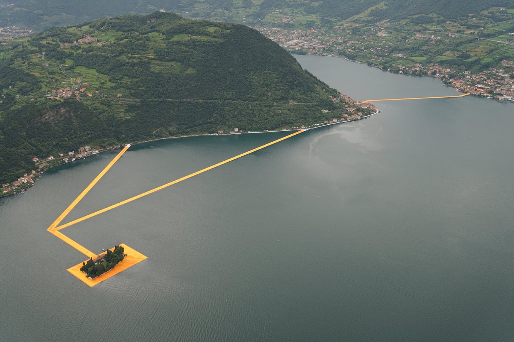 In the morning of June 16, unfurling of 1000,000 square meters of shimmering yellow fabric on the piers and pedestrian streets in Sulzano and Peschiera Maraglio is nearly completed. Image © Wolfgang Volz.