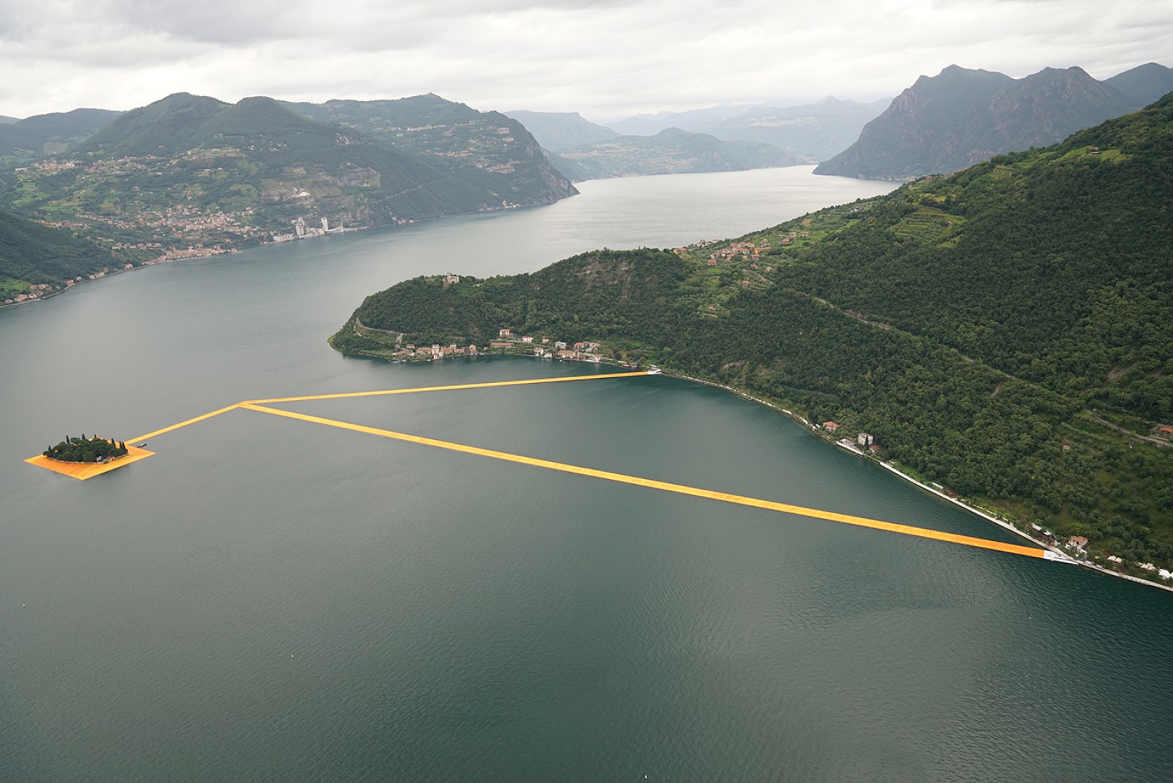 In the morning of June 16, unfurling of 1000,000 square meters of shimmering yellow fabric on the piers and pedestrian streets in Sulzano and Peschiera Maraglio is nearly completed. Image © Wolfgang Volz.