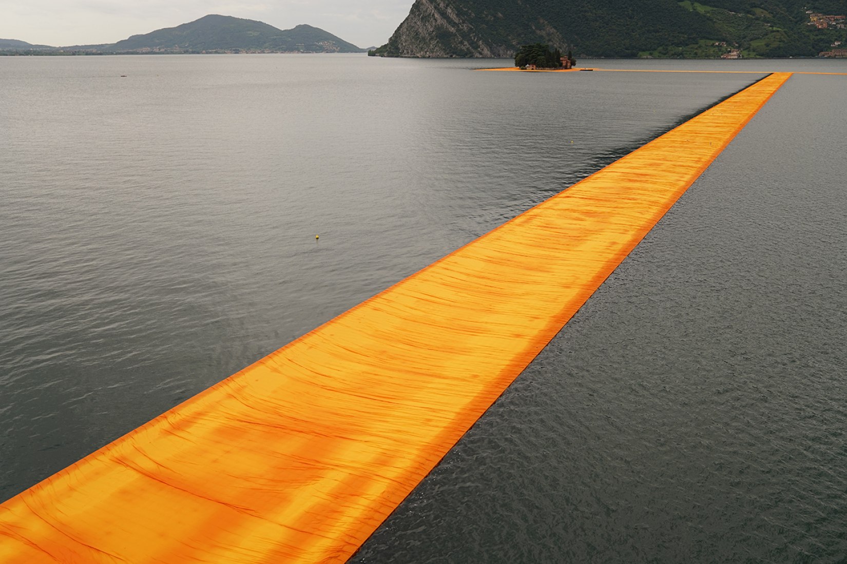 In the morning of June 16, unfurling of 1000,000 square meters of shimmering yellow fabric on the piers and pedestrian streets in Sulzano and Peschiera Maraglio is nearly completed. Image © Wolfgang Volz.