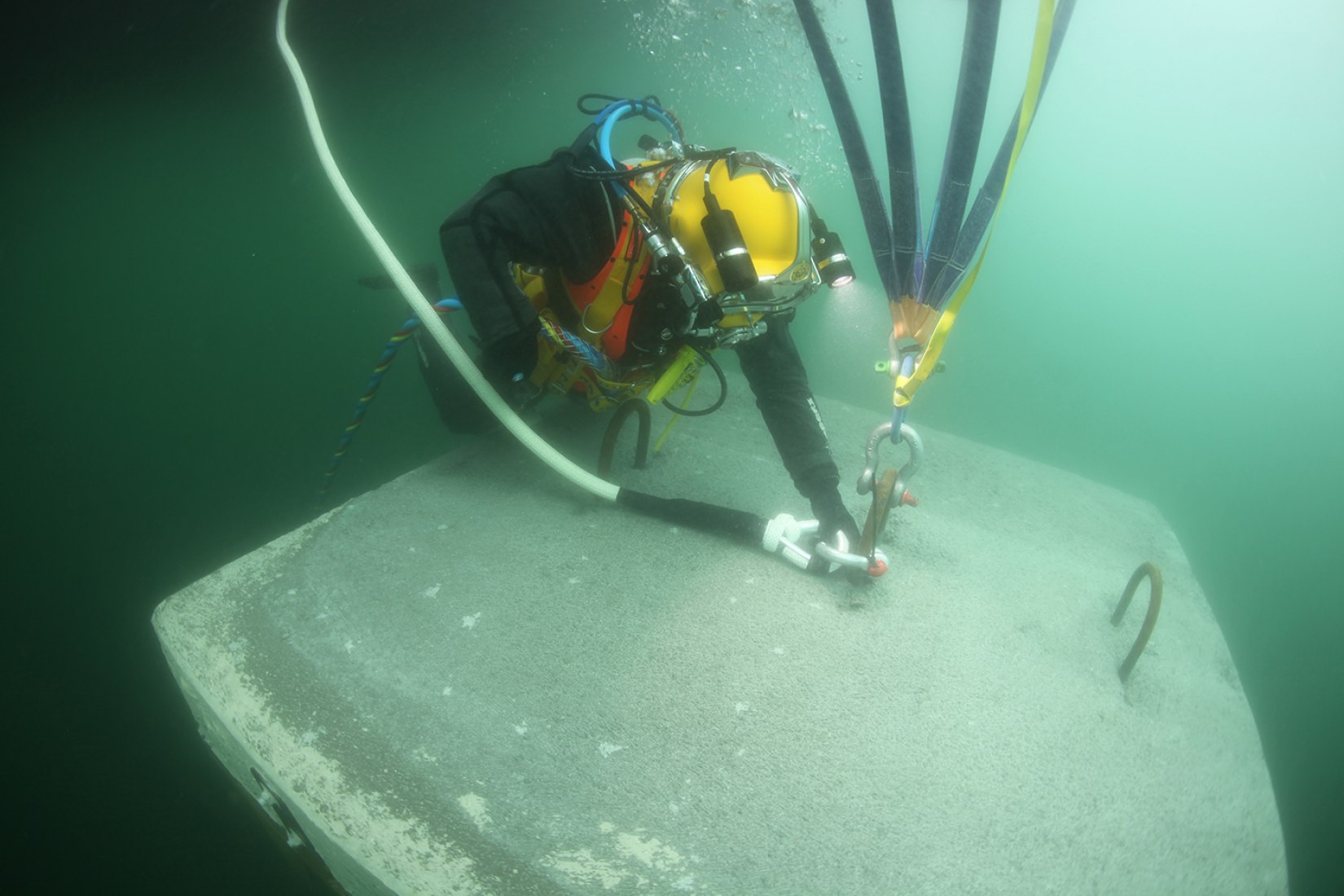 A diver connects a rope made of ultra-high-molecular-weight polyethylene (UHMWPE), covered with a polyester protective layer with a breaking load of 20 metric tons, to one of the anchors on the lakebed to keep the piers in place, March 2016. Image © Wolfgang Volz.